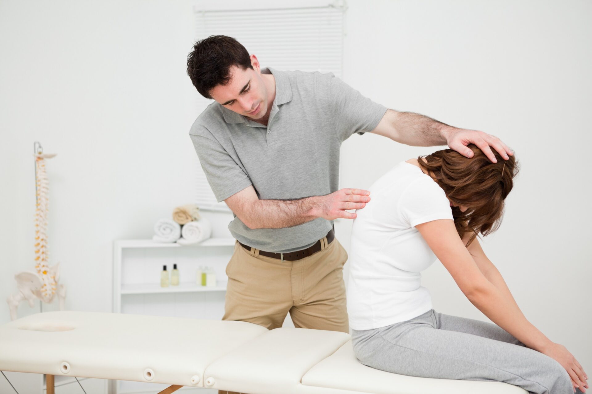 A girl lying on a bed receiving a spinal misalignment test from a chiropractor